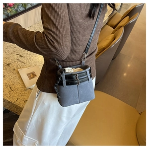 Détail d'un sac seau en daim bleu-gris avec ceintures noires et cordon de serrage