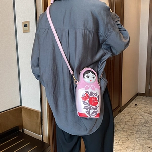 Pink Matryoshka doll shaped crossbody bag with floral patterns on a fashion model
