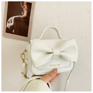 Détail du mini sac à main blanc avec grand nœud et attaches métalliques dorées