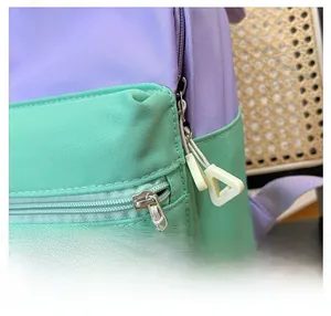 Detailed close-up of smooth metal zipper and blue T letter patch on kids backpack