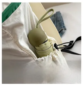 Détail de la poche latérale du sac à dos blanc contenant un parapluie capsule vert