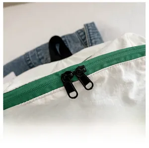 Détails des doubles fermetures éclair vertes sur un sac à dos en nylon blanc