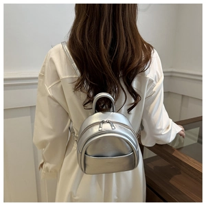 Detail of silver metallic mini backpack with smooth leather finish and sleek top handle