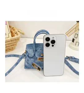 Mini sac à bandoulière en jean bleu comparé à un smartphone sur une table blanche