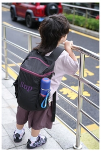 Détails d'un sac à dos enfant noir en nylon avec fermetures éclair violettes et poche latérale