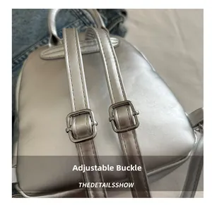 Detail view of adjustable silver metal buckle and stitching on silver mini backpack strap
