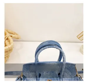 Détail des poignées confortables en denim bleu clair et des finitions métalliques dorées