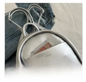 Detailed shot of silver metallic mini backpack featuring front pocket and embossed logo