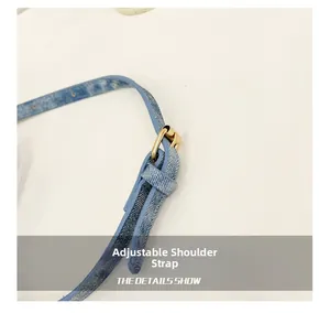 Détail de la bandoulière réglable en denim bleu avec boucle dorée et couture fine