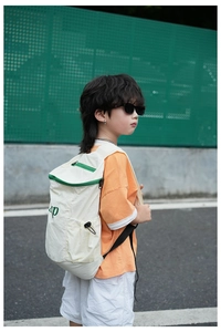 Vue extérieure d'un enfant portant un sac à dos blanc et vert avec sangles réglables