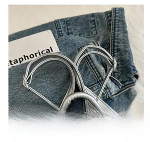 Detail of silver leather backpack straps and polished metal zippers on denim background