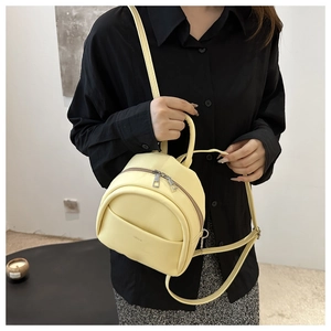 Detail of a bright yellow mini backpack in matte PU leather with metal zipper and ring handle