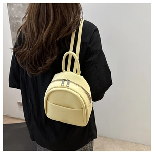 Detail shot of a yellow mini synthetic leather backpack worn by a child from the back