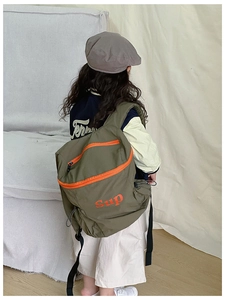 Détail d'un sac à dos enfant en nylon vert avec fermeture éclair orange et imprimé
