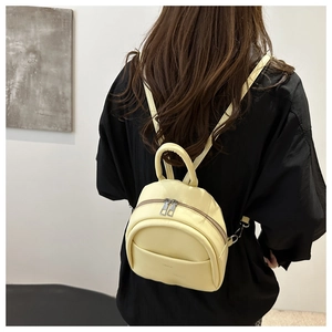 Detail view of cream leather mini backpack on model showing adjustable straps and soft texture