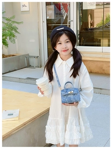 Photo en extérieur d'un petit sac bandoulière en denim bleu porté par une petite fille