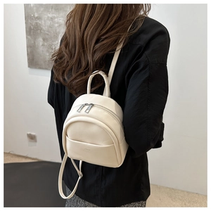 Close-up of a cream faux leather mini backpack showing smooth texture and silver zipper