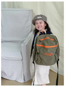 Sac à dos enfant vert olive avec zip orange et logo Sup porté par une petite fille