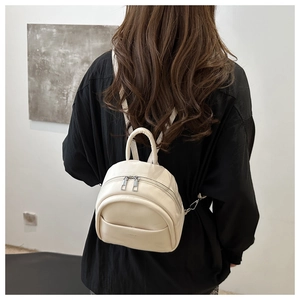 Detail of a minimalist cream white faux leather mini backpack for children on model