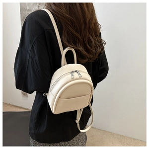 Detail showing the cream faux leather texture and silver zipper of this mini backpack