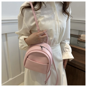 Close-up of pink mini PU leather backpack with adjustable straps on a child model