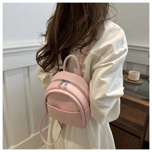 Rear view of a girl wearing a pink mini backpack with smooth leather and top handle