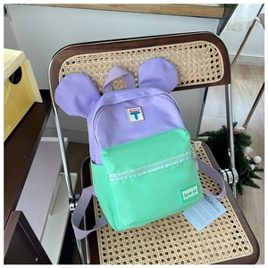 Detail of cute contrast-color kids backpack with round ears on woven chair