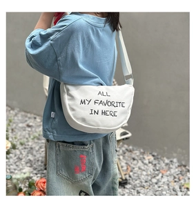 Detail of white canvas half-moon crossbody bag with black hand-drawn letter print