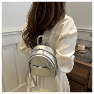 Rear view of a silver metallic mini backpack for kids shown in a minimalist setting