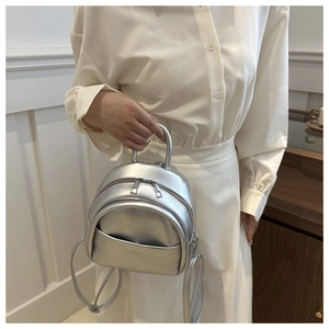 Detail of silver metallic mini backpack for kids featuring adjustable straps and zipper