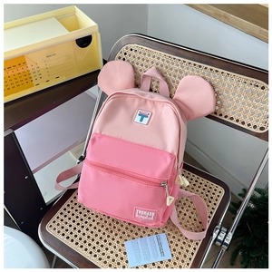Detail view of pink student backpack with cute round ears on a woven chair