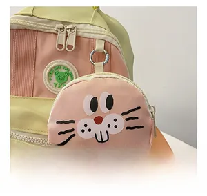Detail showing the cute pink cartoon bunny pendant on a yellow and pink kids backpack