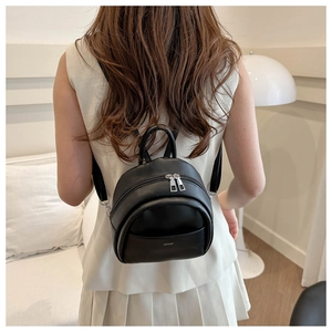 Rear view of model wearing a minimalist black leather mini backpack with silver zippers
