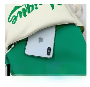 Detailed close-up of large-capacity front pocket on green and white canvas backpack