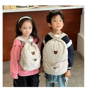 Détail de deux tailles de sacs à dos ours mignons en crème portés par des enfants