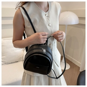 Close-up of black leather mini backpack featuring silver zippers and adjustable straps