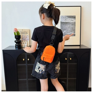 Kind trägt eine leuchtend orangefarbene Mini-Nylontasche mit verstellbarem Riemen