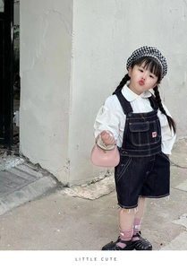 Detail of kids denim overalls set featuring white puff sleeve shirt and check beret