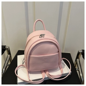 Pink mini faux leather backpack with silver zippers and aimai logo on white books