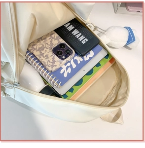 Top view of spacious main compartment in creamy white backpack showing books and gadgets