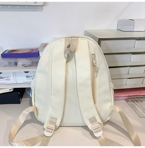 Detail view of the beige backpack featuring adjustable straps and a hidden anti-theft back pocket