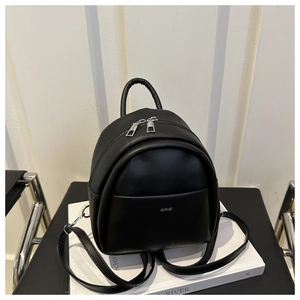 Close-up of a mini black leather backpack with silver brand logo and dual zippers