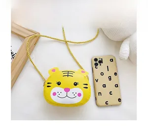Detail shot of a yellow tiger-shaped mini crossbody bag for kids with comparison scale