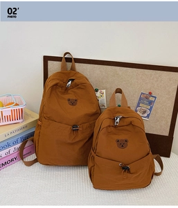 Détail de sacs à dos en toile marron en deux tailles avec broderie ours et cordon de serrage