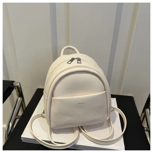 Detailed close-up of cream mini backpack featuring soft faux leather texture and logo pocket