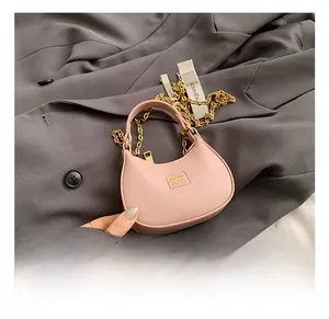 Detail showing pink mini leather bag with chunky gold chain strap and embossed logo