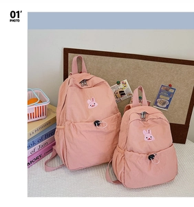 Vue détaillée d'un ensemble de sacs à dos roses avec broderie lapin et poches à cordon