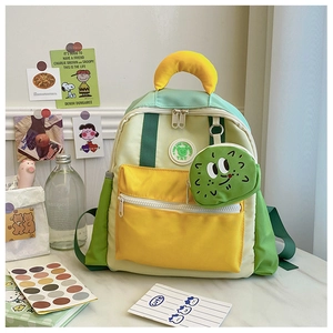 Detail of color-block kids backpack with cute round cartoon charm and badge