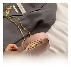 Detailed view of pink mini PU leather handbag with gold chain strap and smooth top handle