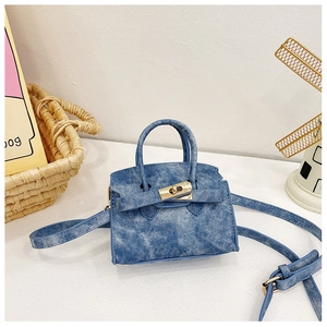 Détail du mini sac en denim bleu avec fermoir rotatif doré et texture raffinée